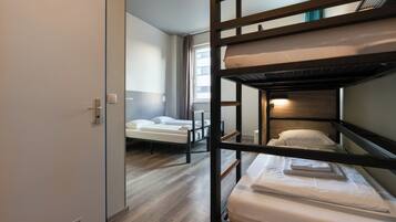 Quarto com beliche, piso de madeira, porta branca e janela com cortinas.