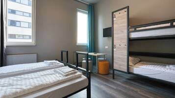 Une chambre avec un lit superposé, un bureau, une chaise, un radiateur et une fenêtre avec des rideaux.