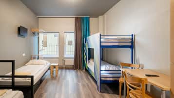 A dormitory room with bunk beds, a desk, and a chair.