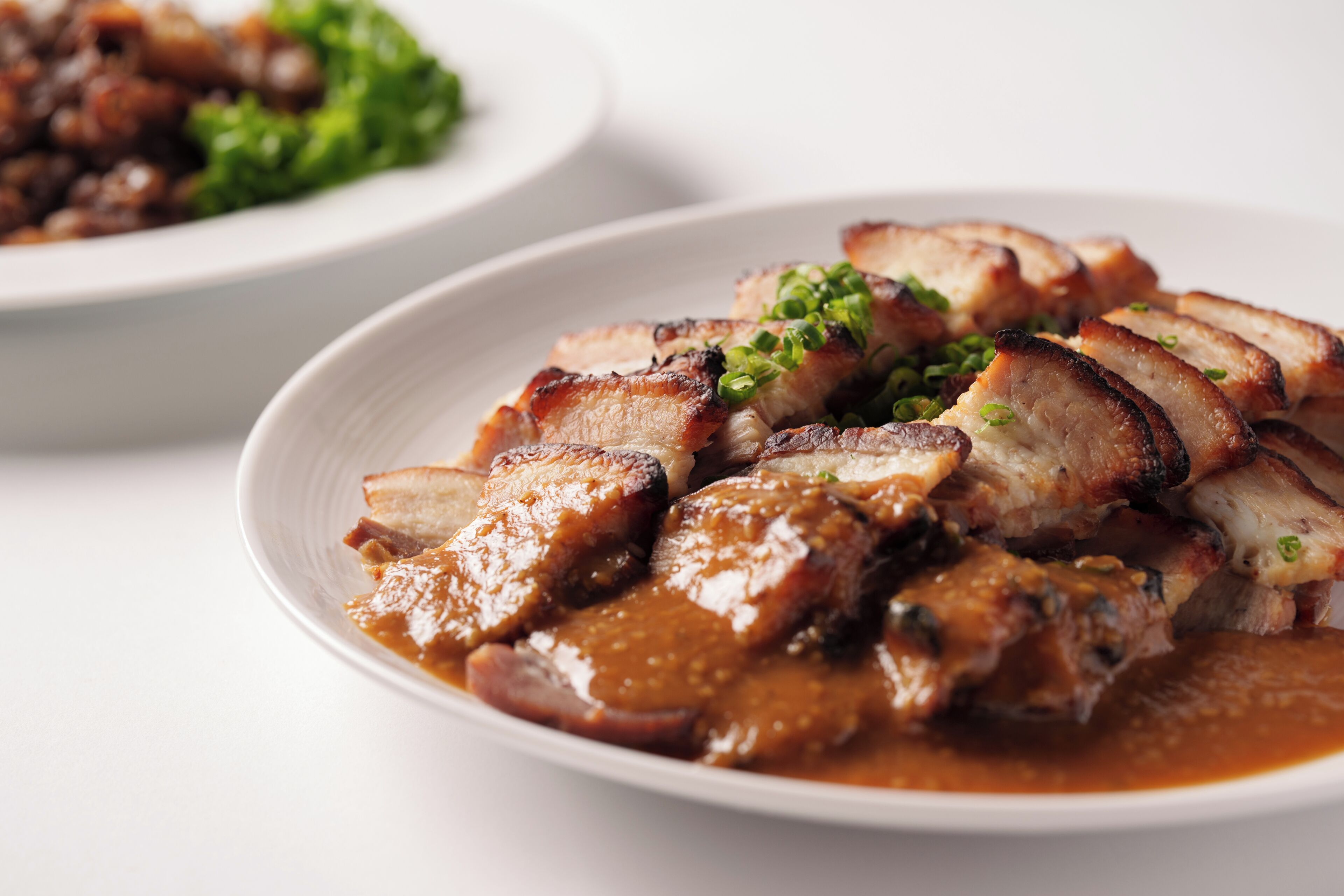 A plate of sliced meat with a sauce and garnish.