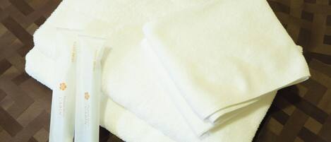 A white towel and a tube of toothpaste on a patterned surface.