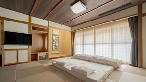 A room with tatami flooring, a bed, a television, and a large window with curtains. - Premier Hotel Cabin Obihiro (Obihiro)