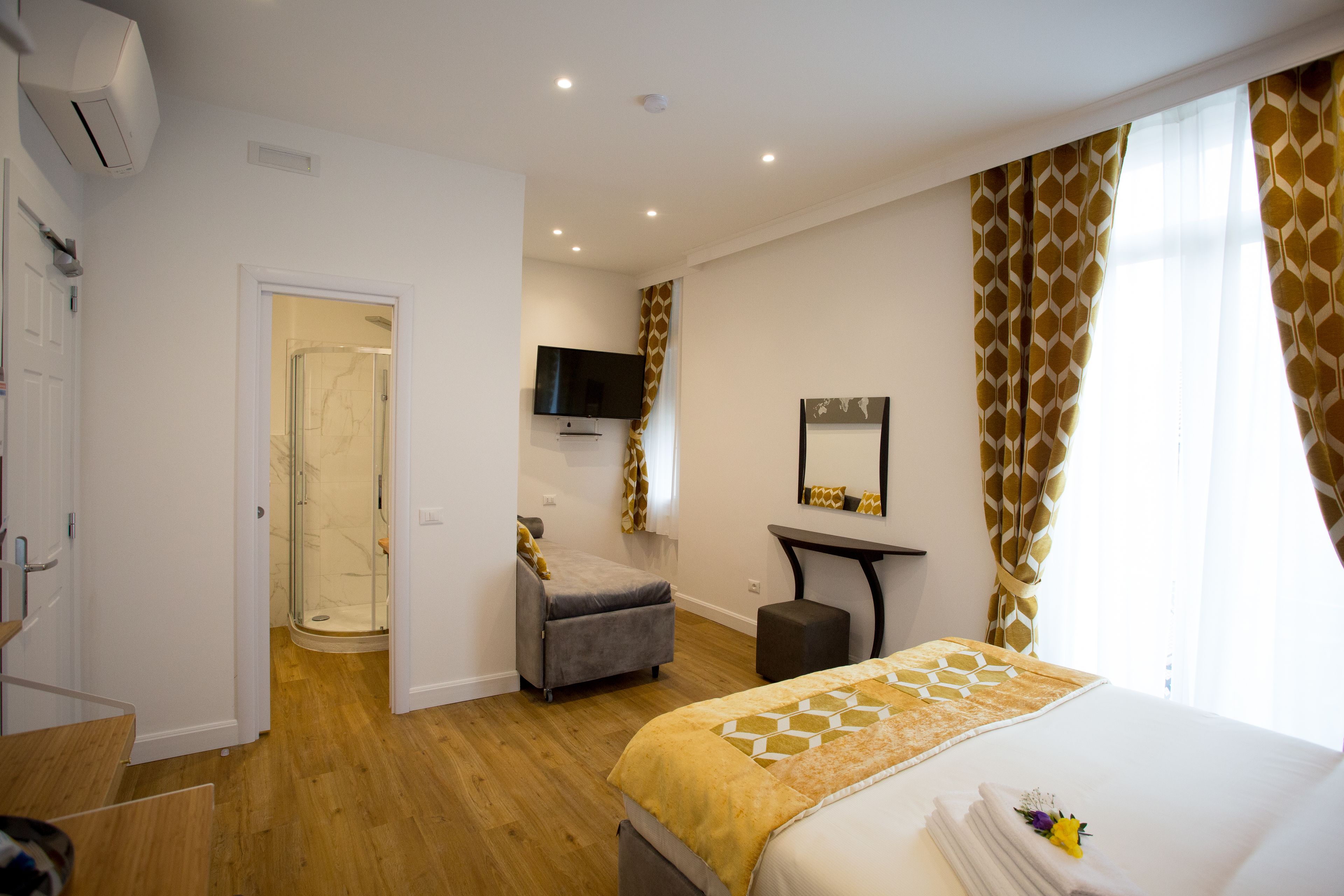 A hotel room with a bed, a desk, a television, and a shower.