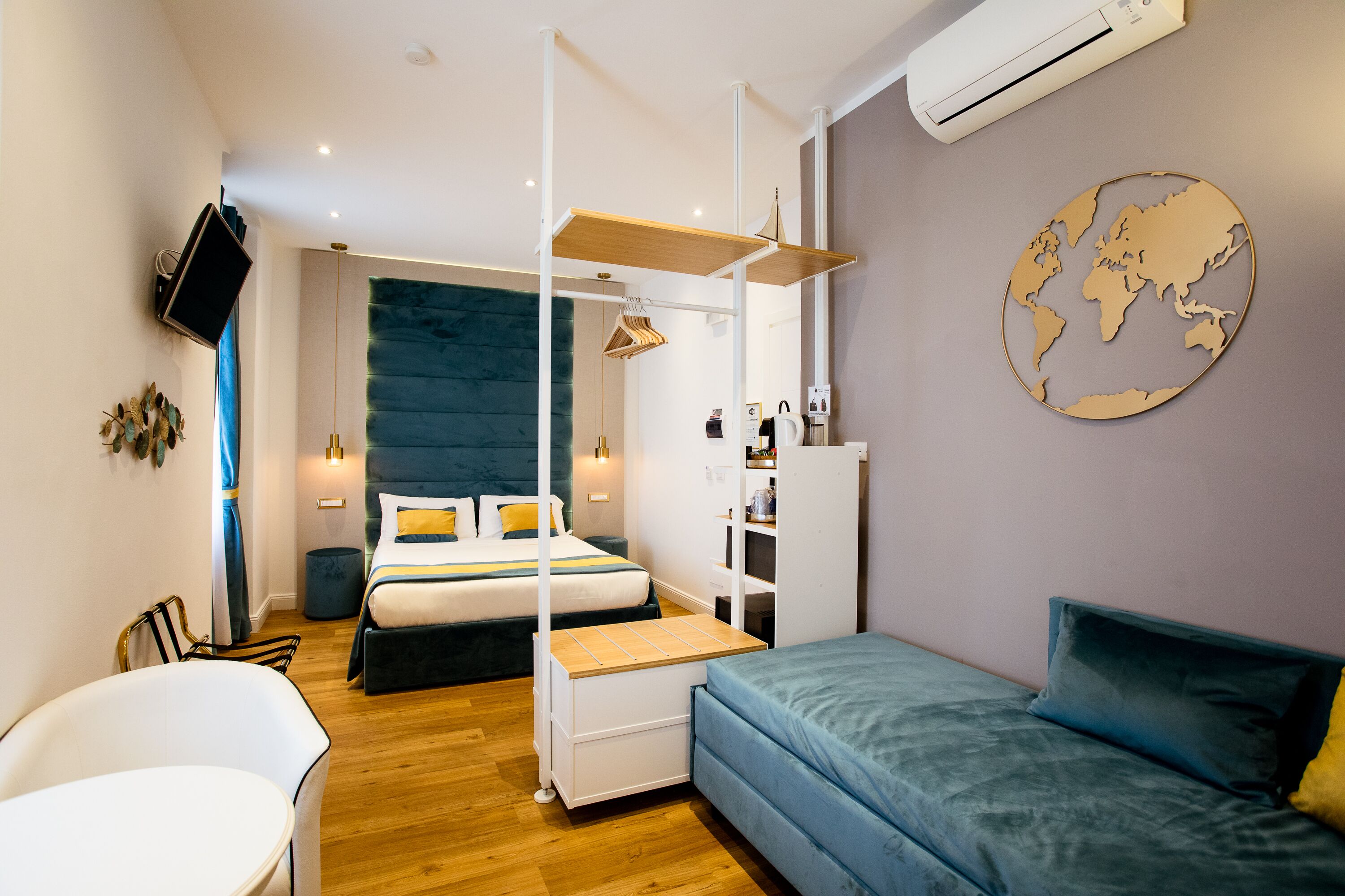 A modern hotel room with a bed, a sofa, a desk, and a TV.