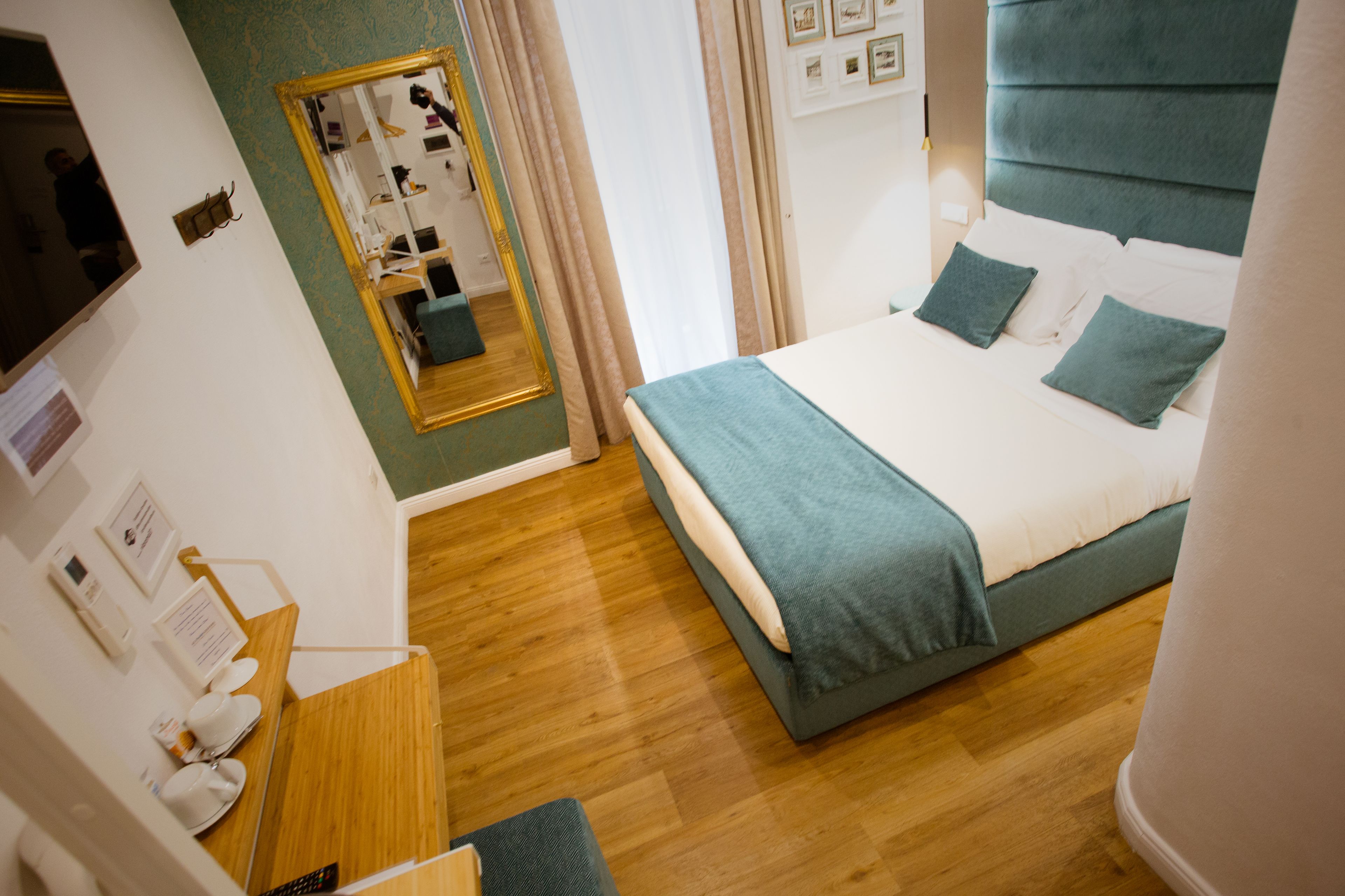 A hotel room with a bed, a desk, a mirror, and a wardrobe.