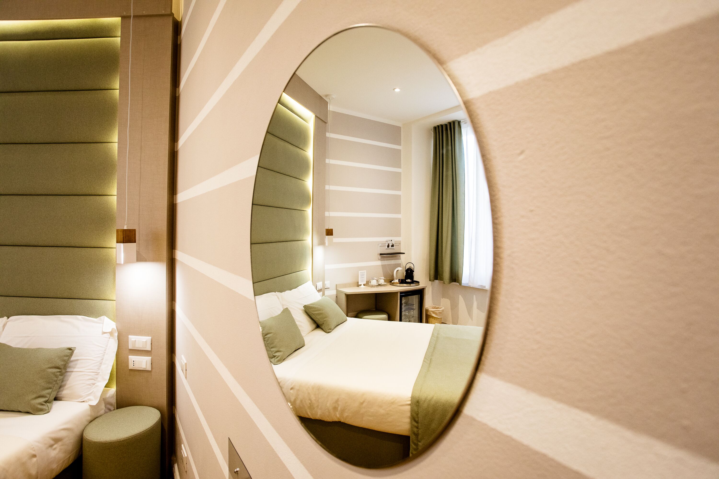Ein modernes Hotelzimmer mit einem großen Bett, einem Nachttisch, einem Spiegel und einer kleinen Sitzecke.