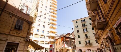 Vista de la calle con edificios, una noria y un letrero que dice 'MAGAZETTA SPEZZIN'.