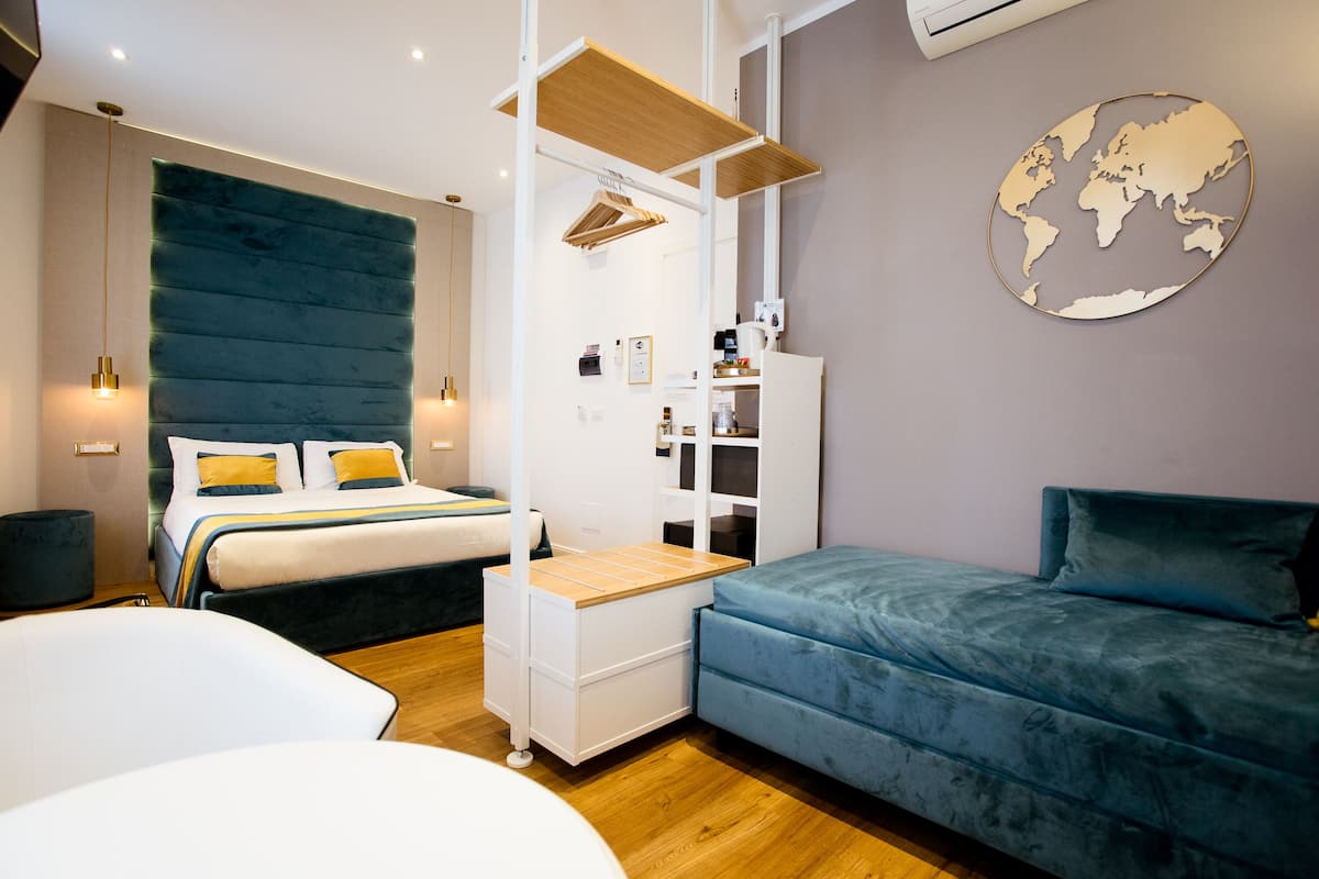 Ein modernes Schlafzimmer mit Bett, Sofa, Schreibtisch und einer Weltkarte an der Wand.