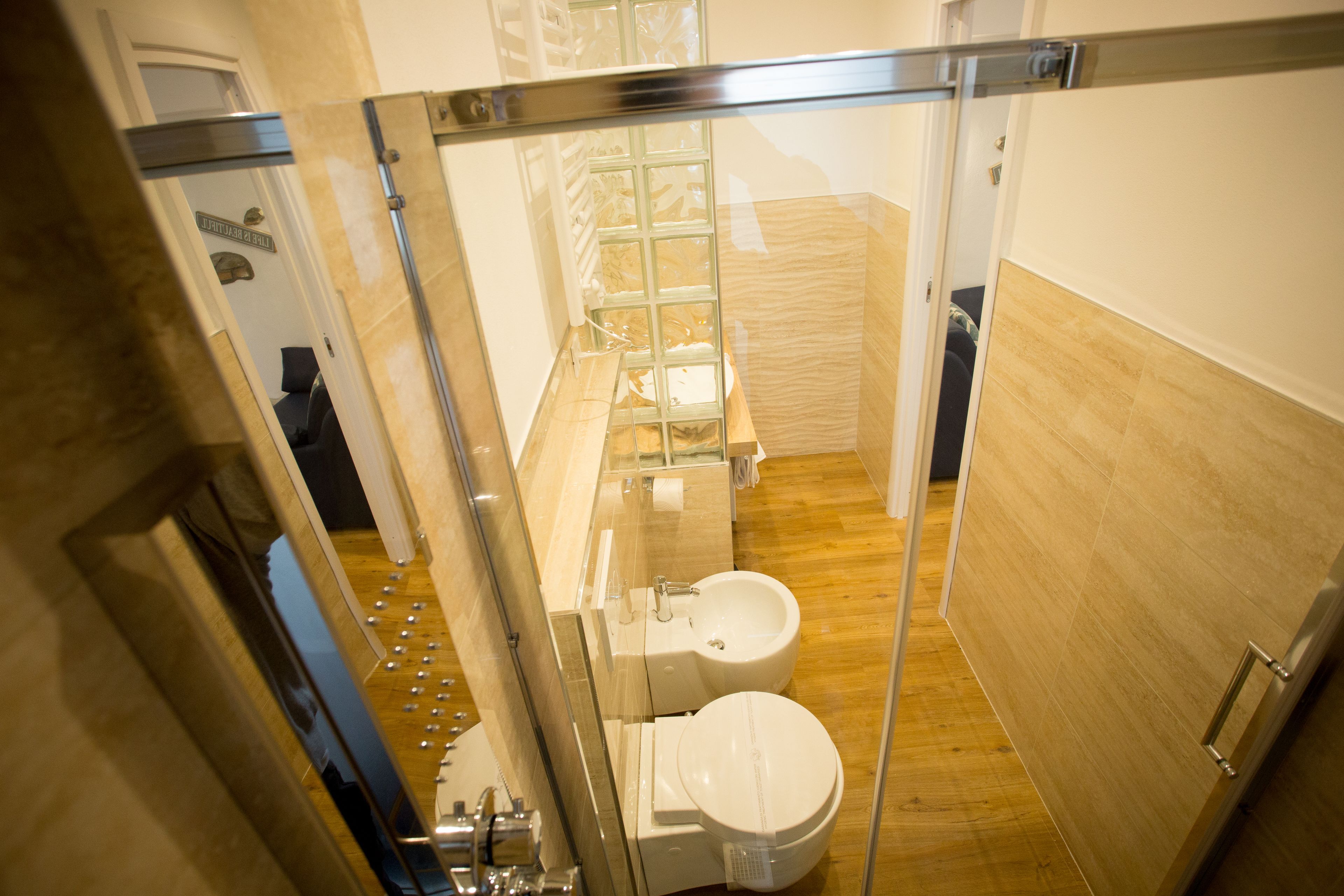 Een moderne badkamer met een glazen douchecabine, toilet en een bidet.