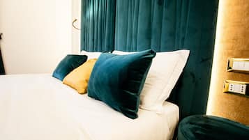 A bed with white and teal bedding, a yellow pillow, and teal pillows.