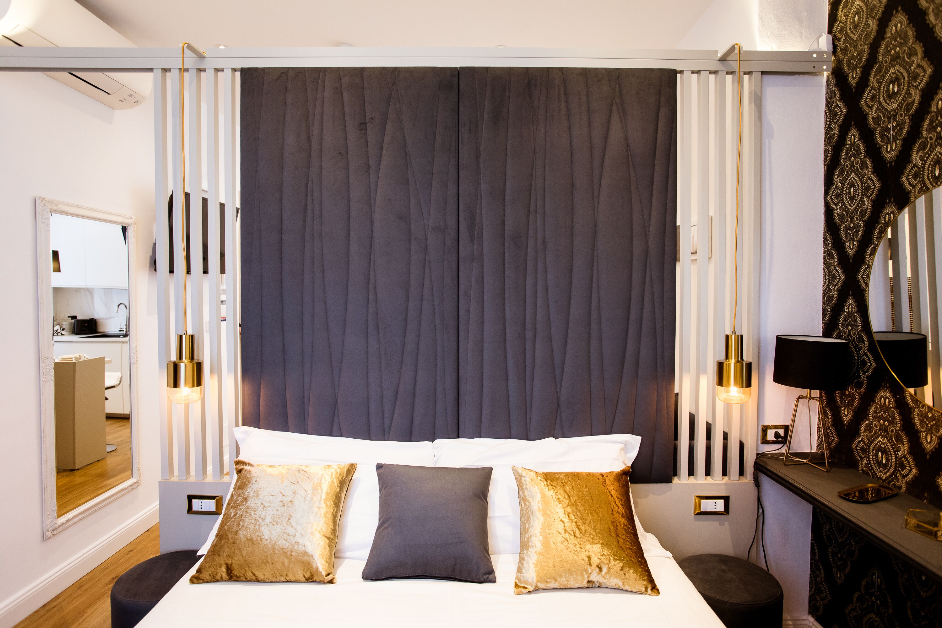 Habitación de hotel moderna con una cama grande, lámparas de noche, un espejo y un escritorio con lámpara.
