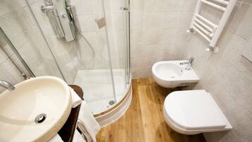 Ein Badezimmer mit Duschkabine, Waschbecken, Bidet und Toilette.