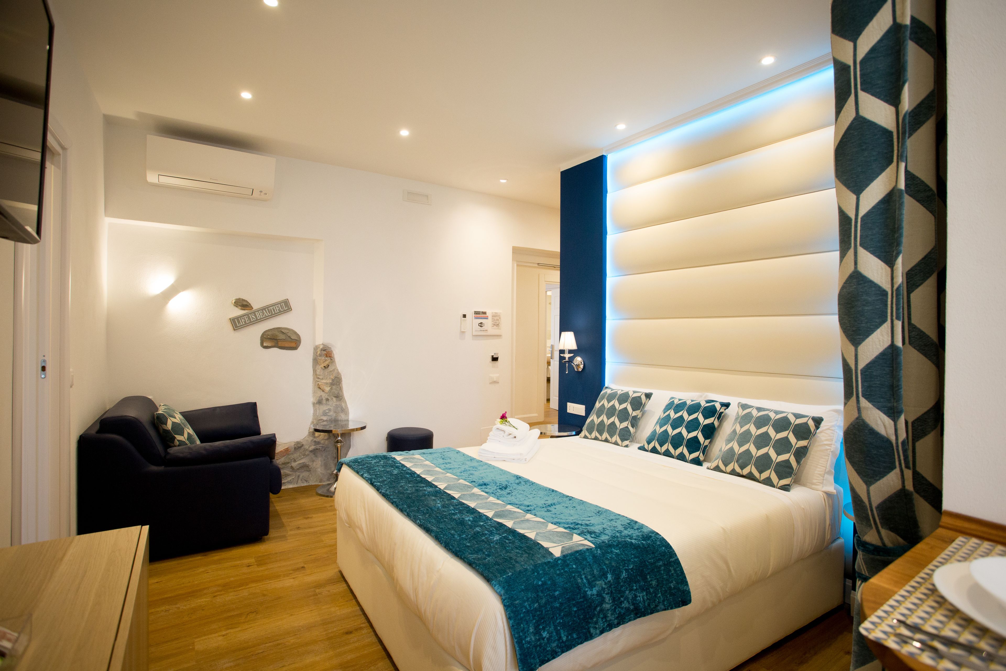 A modern bedroom with a large bed, a sofa, and a small table.