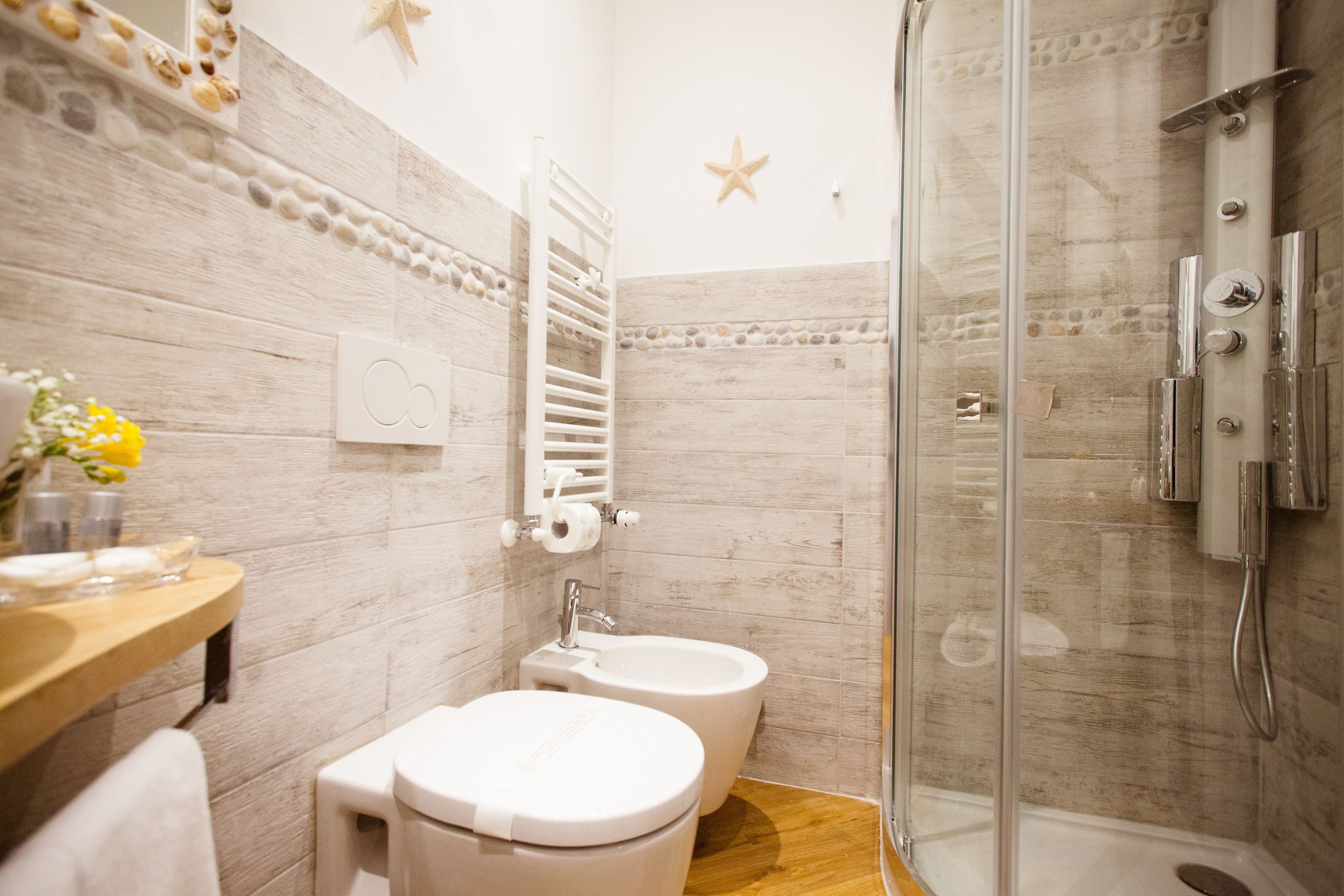 A bathroom with a shower, toilet, bidet, and a vanity with a mirror and towel.