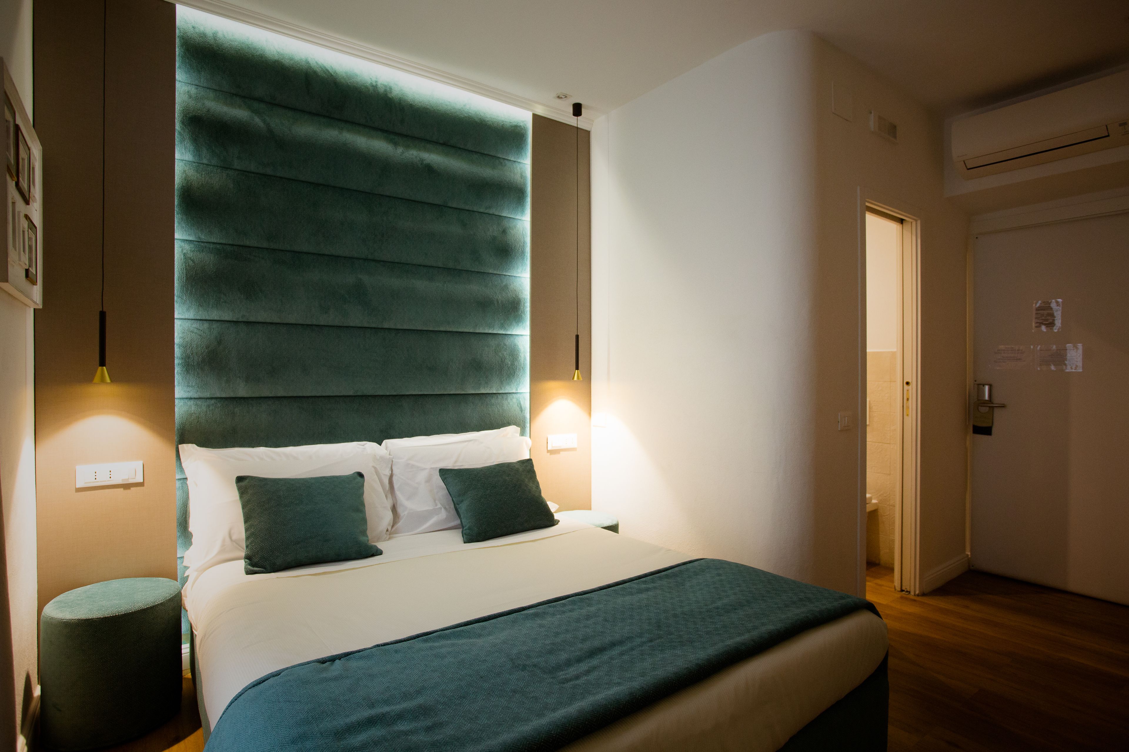 A neatly arranged hotel room with a large bed, a bedside table, and a wall-mounted light fixture.