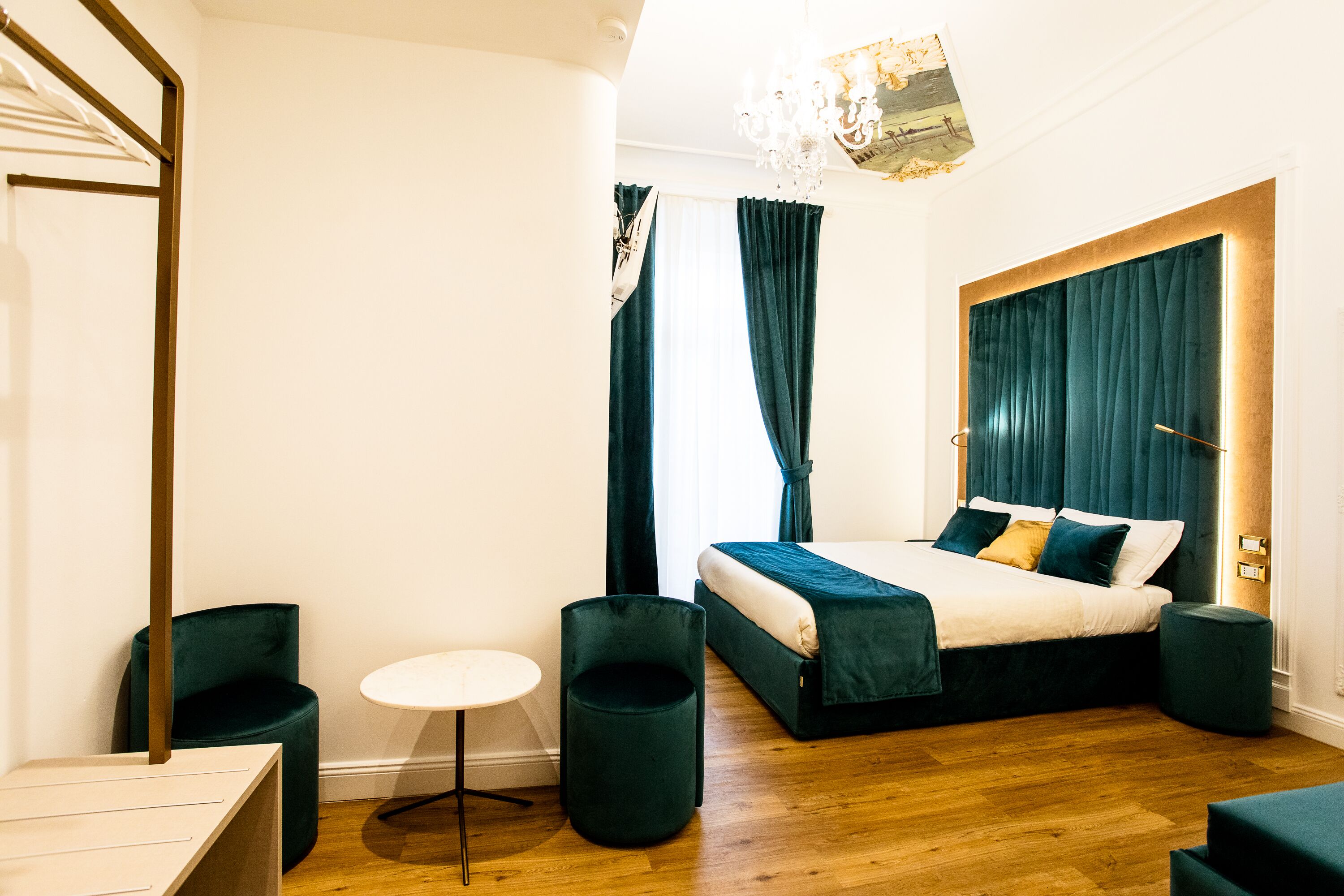 A modern bedroom with a wooden floor, a bed with dark bedding, a round table, and a chair.