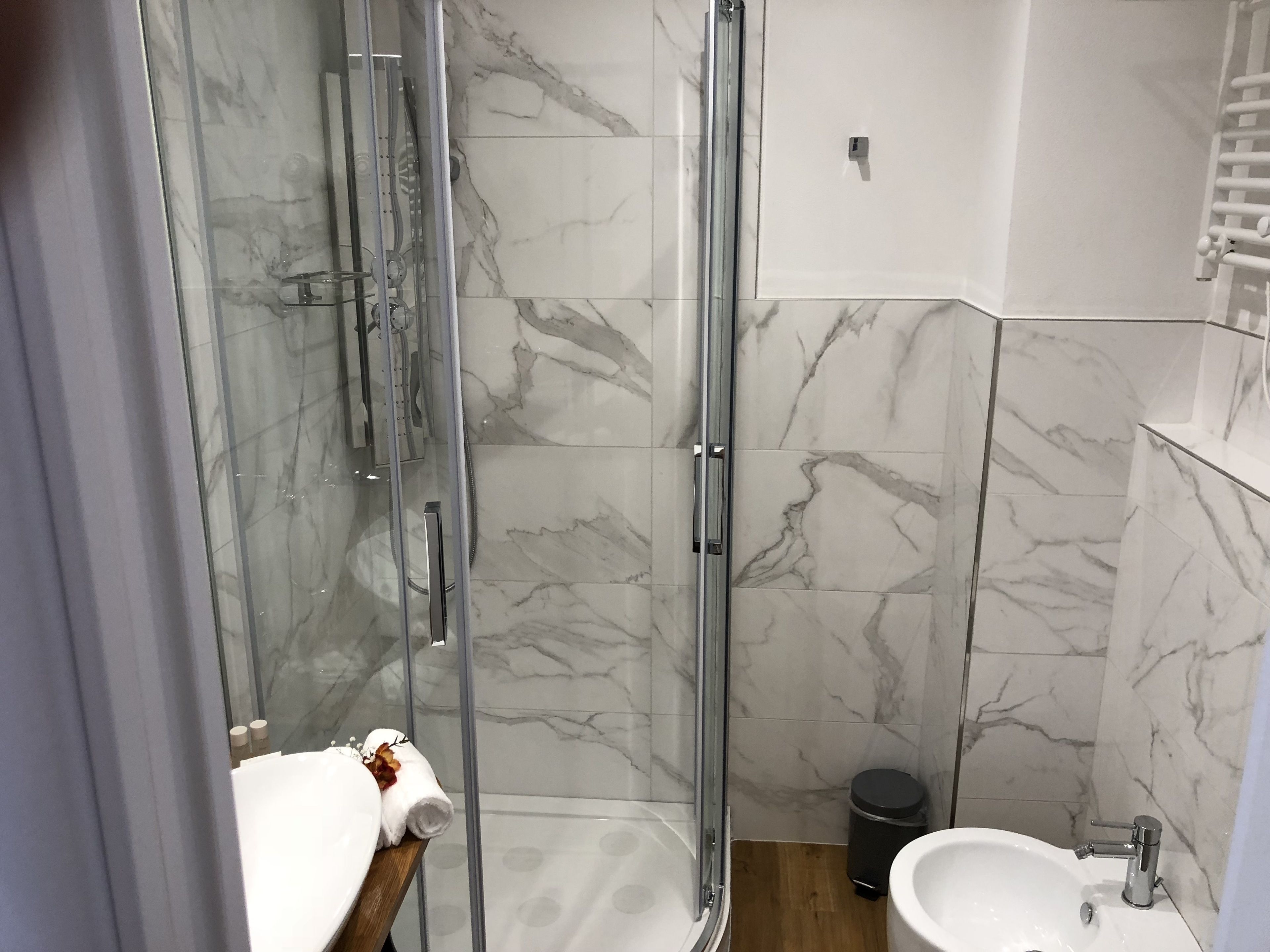 A modern bathroom with a glass shower enclosure, a wooden vanity with a sink, and a toilet.
