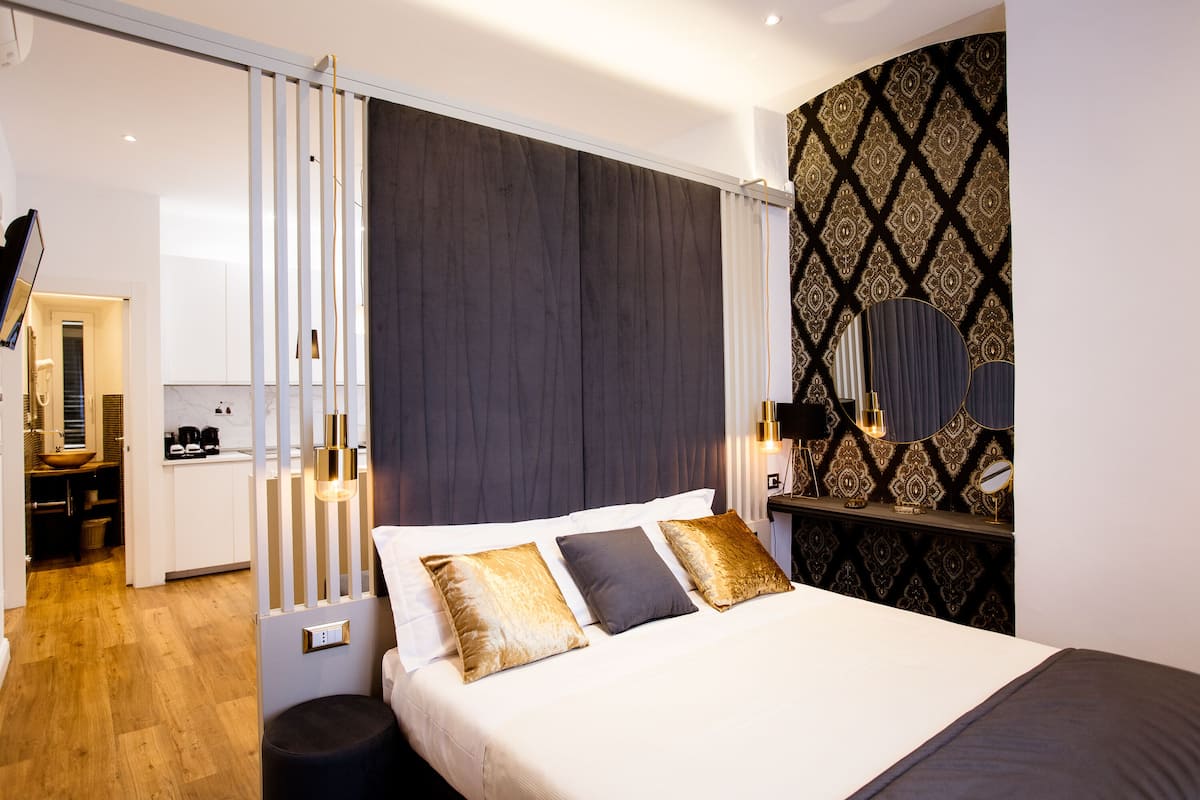 Ein modernes Hotelzimmer mit einem großen Bett, einem Nachttisch mit Lampe und einem dekorativen Spiegel.