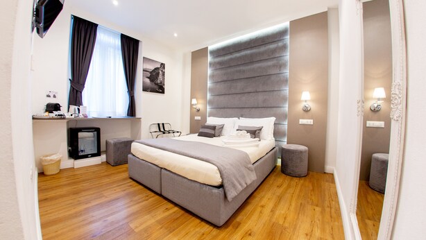 A modern bedroom with a large bed, bedside lamps, a small TV, and a window with curtains. - Atmosfere Guest House - 5 Terre e La Spezia (La Spezia)