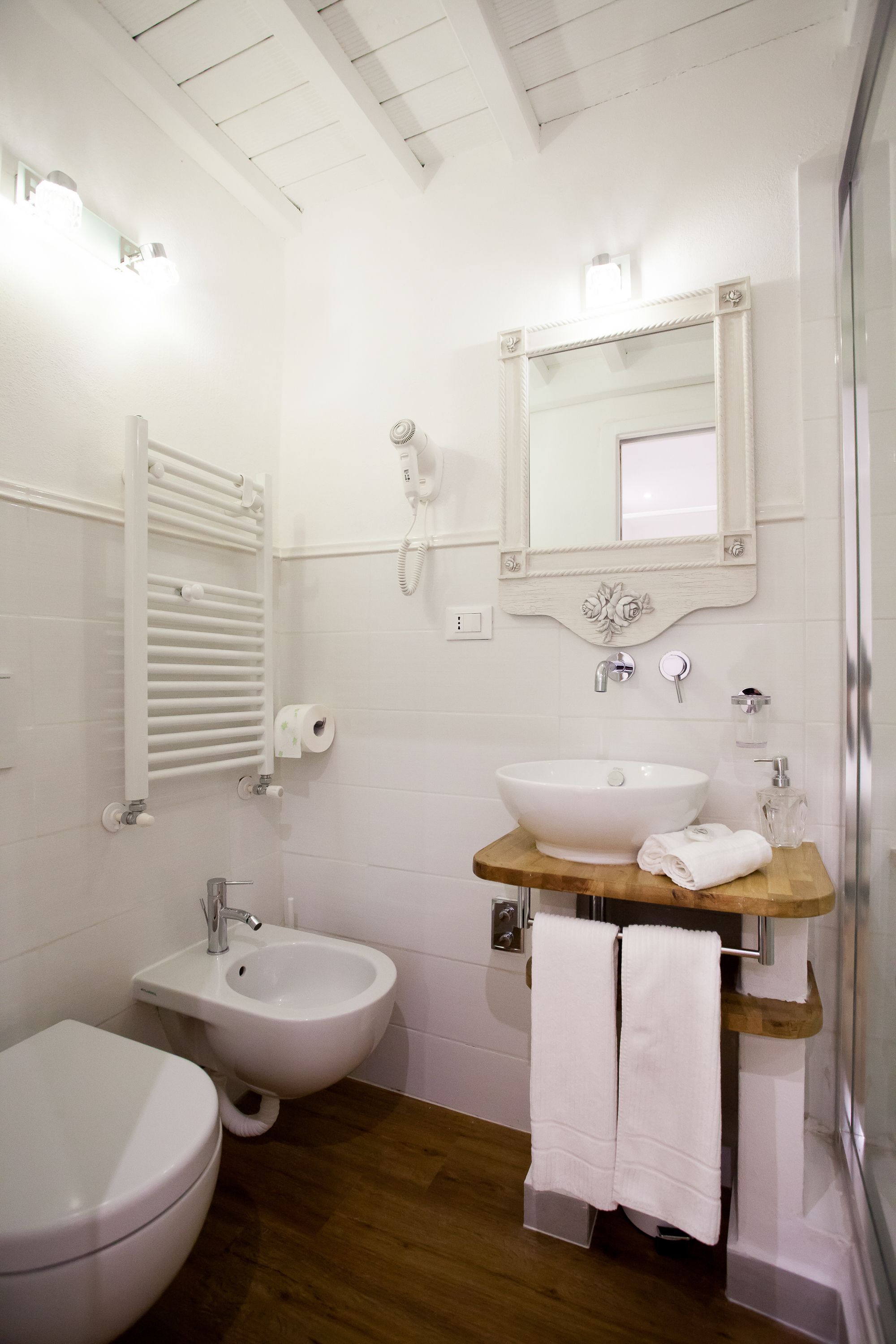 A bathroom with a toilet, bidet, sink, and a mirror above the sink.