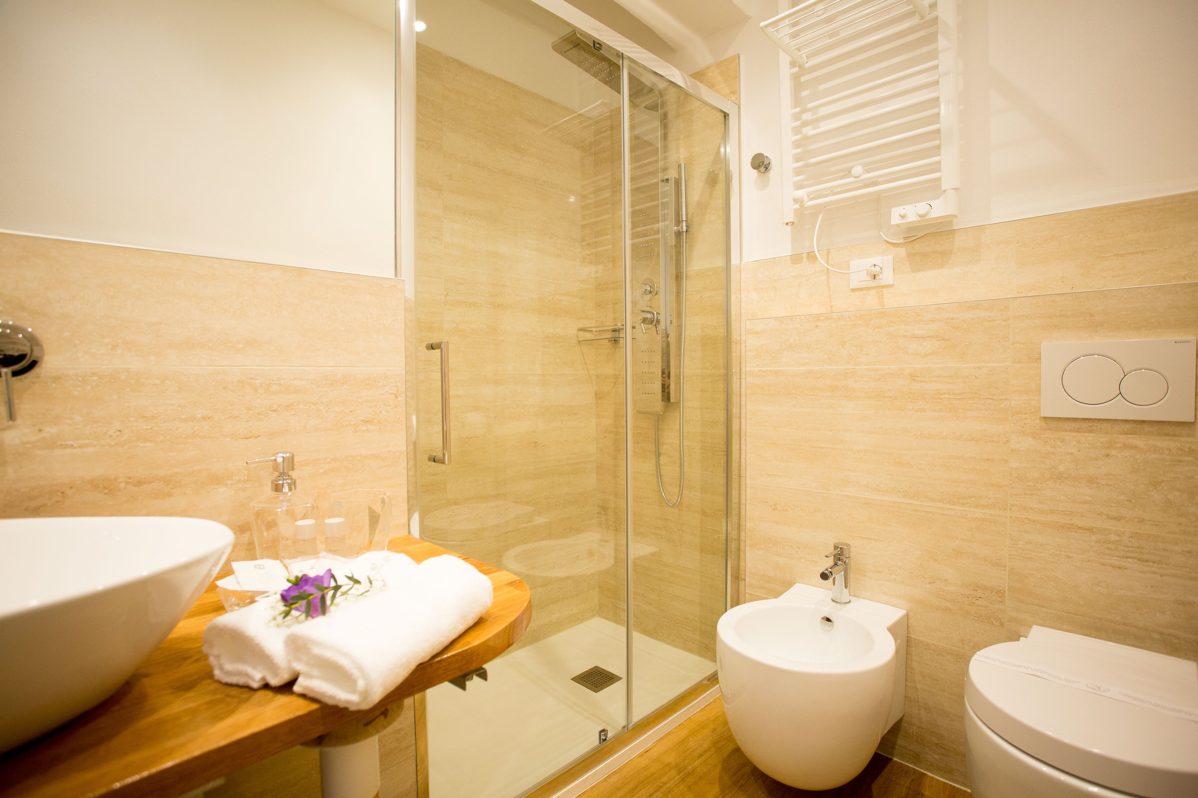 Une salle de bain moderne avec une douche à parois de verre, un meuble-lavabo en bois doté d’un grand évier et un bidet.