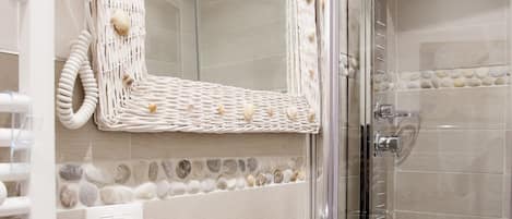 A bathroom with a white sink, a glass shower enclosure, and a wicker mirror.