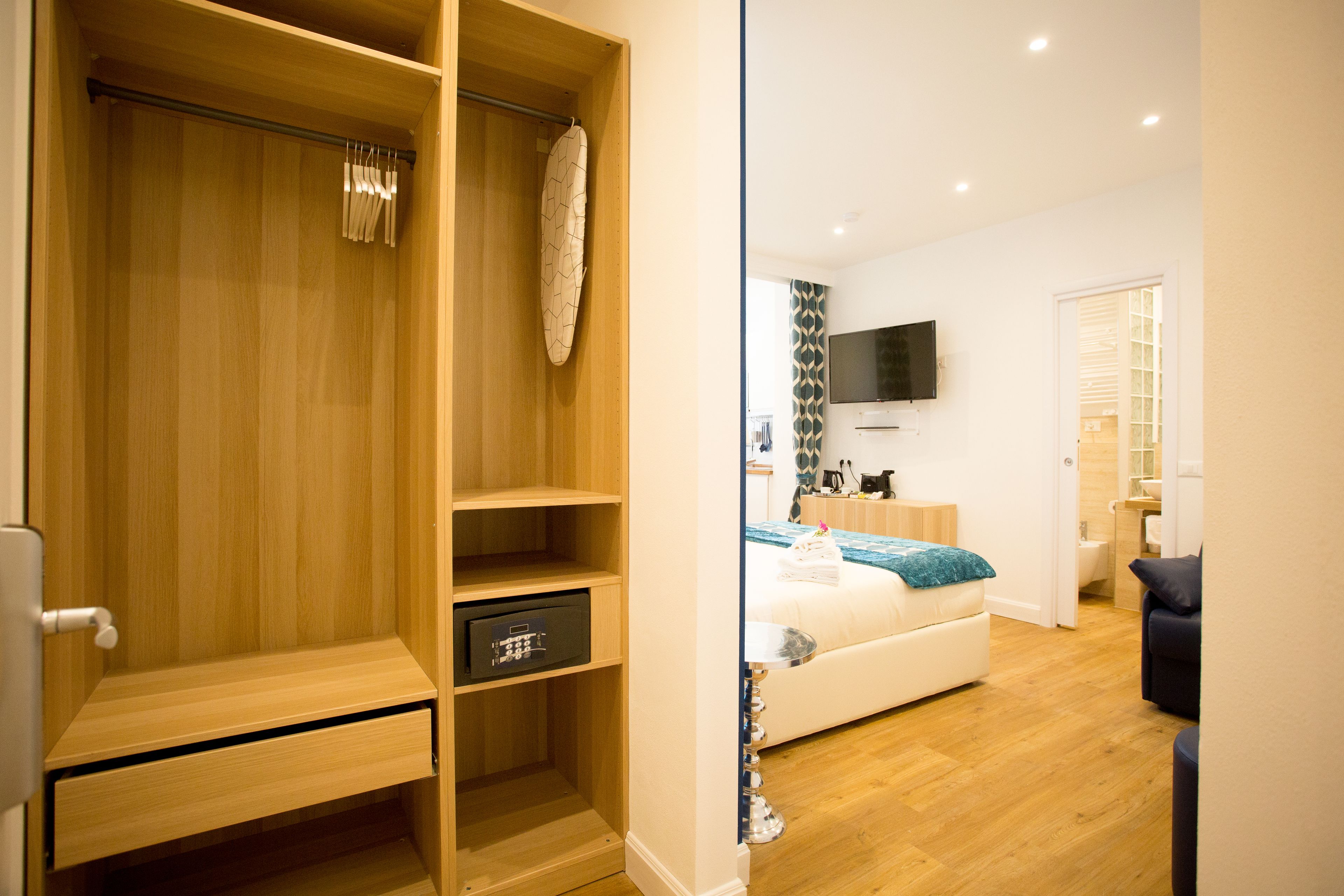 Una camera da letto moderna con un'armadiatura in legno, un letto con coperta blu e una TV a parete.