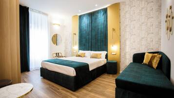 Una habitación de hotel moderna con una cama grande, un sofá más pequeño, una mesa redonda y vistas a la ciudad.