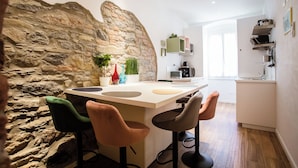 A modern kitchen with a stone accent wall, bar stools, and a central island. - Atmosfere Guest House - 5 Terre e La Spezia (La Spezia)