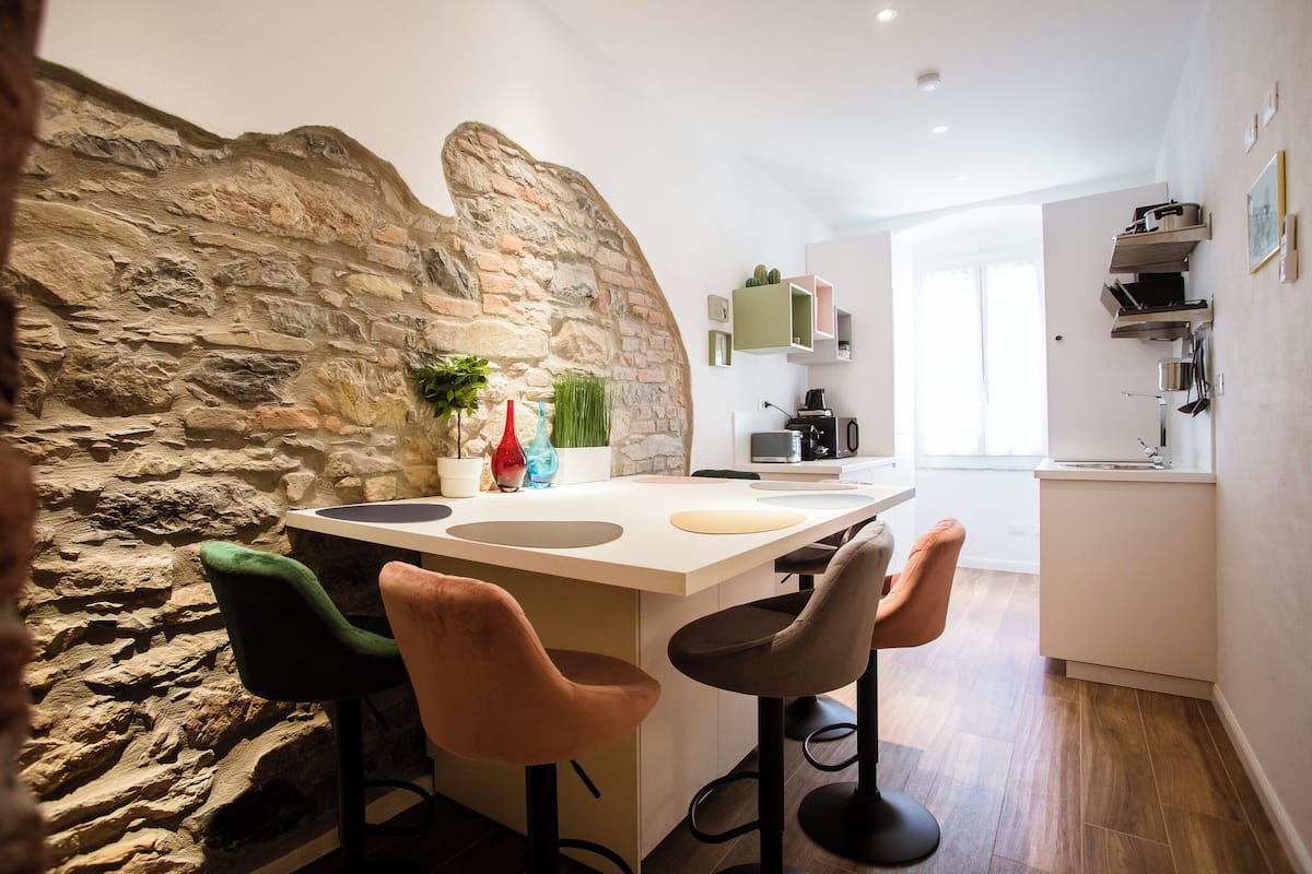 Eine moderne Küche mit Steinwand, Barhocker und einer zentralen Kochinsel.