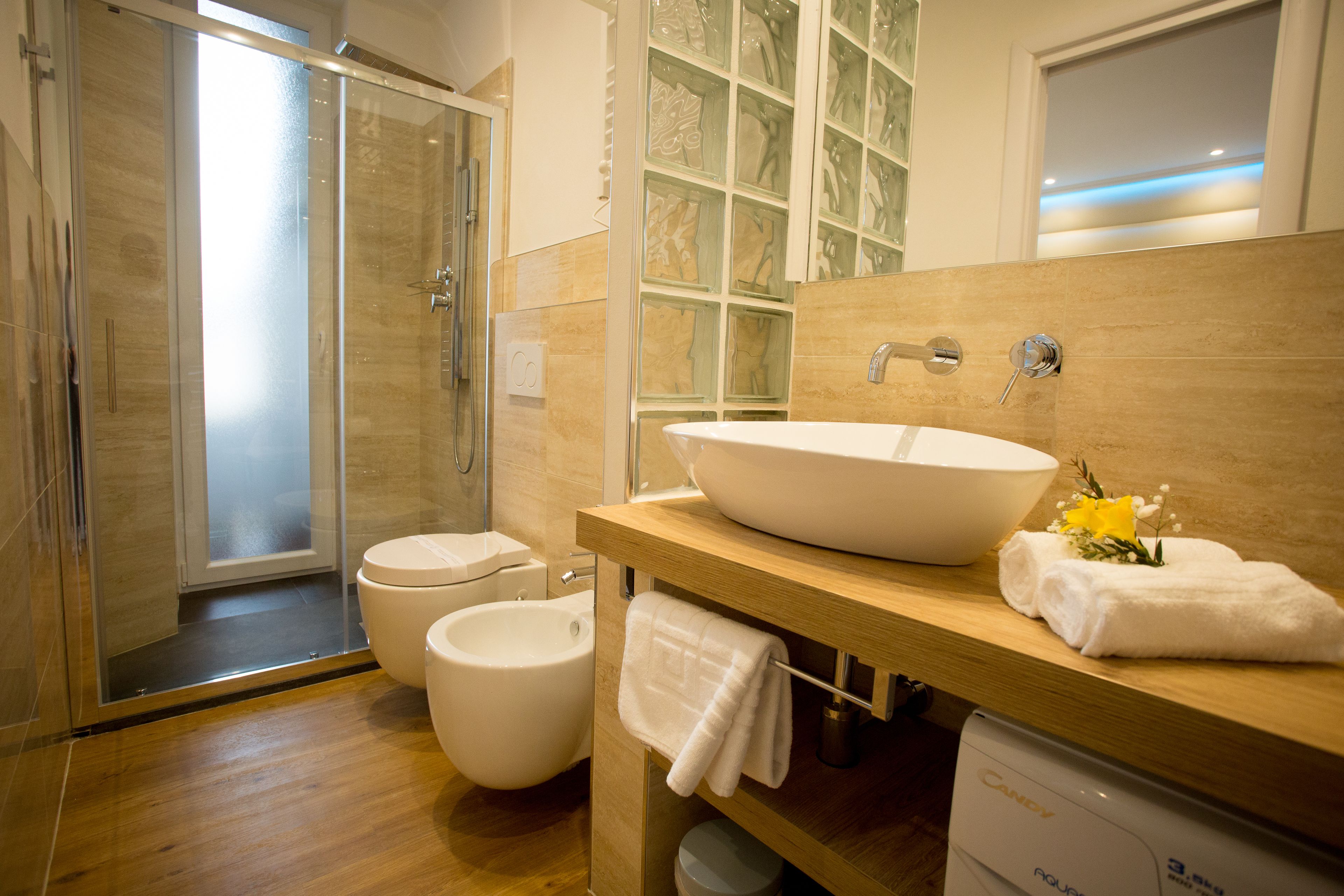 Un baño moderno con ducha de vidrio, lavamanos blanco y bidé.