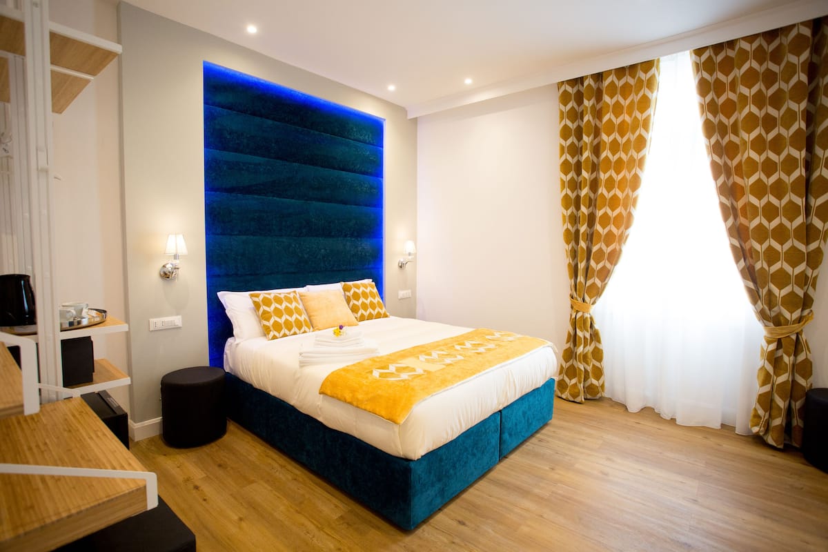 Ein modernes Schlafzimmer mit einem großen Bett, einem blauen Kopfteil und Holzboden.