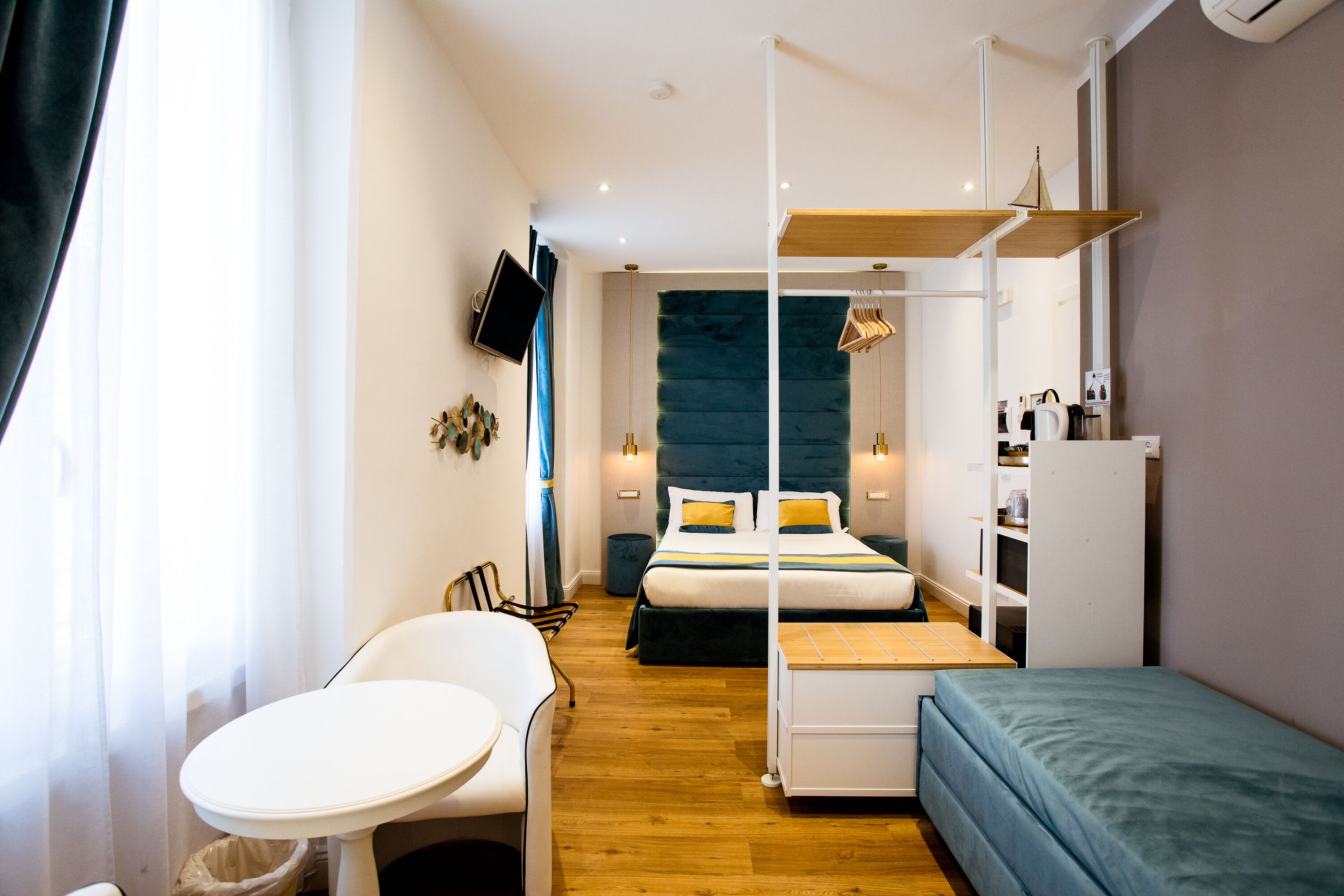 A modern hotel room with a bed, bedside table, chair, and a small desk.