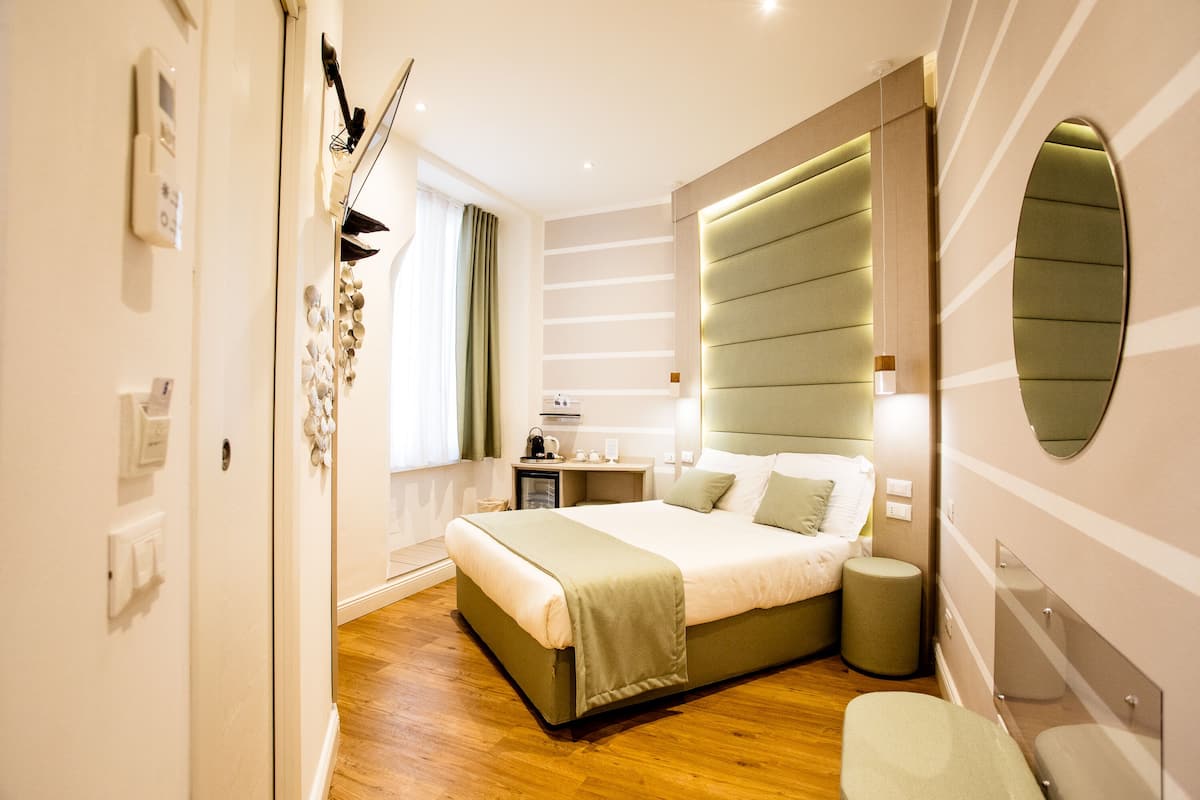 Ein modernes Schlafzimmer mit einem großen Bett, Nachttischen, einem Spiegel und einem Fenster mit Vorhängen.