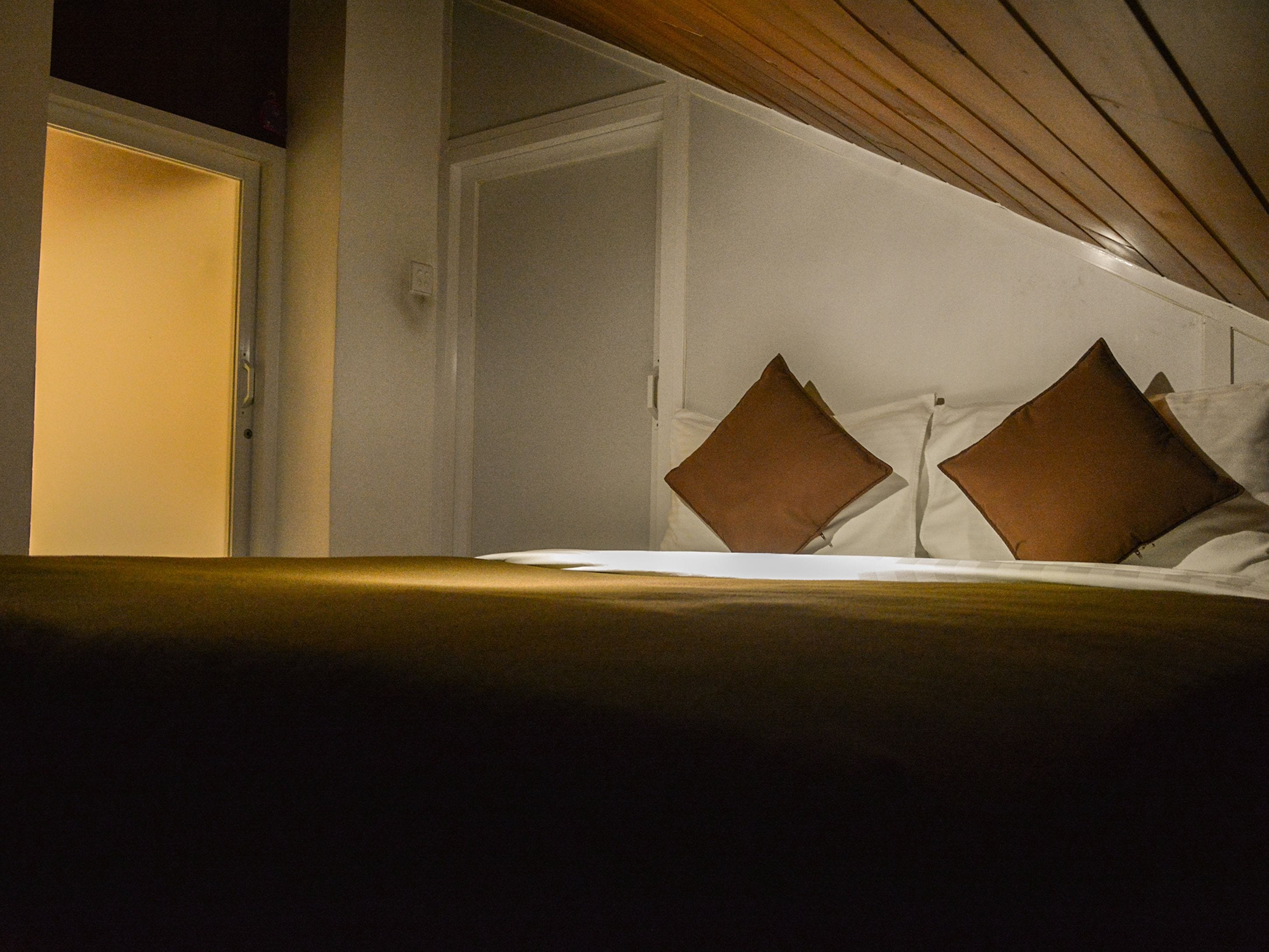 Une chambre d’hôtel avec un lit, deux oreillers et une porte.