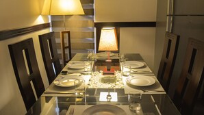 A dining table set for four with a lamp, plates, cutlery, and glasses. - Panoramic Holiday Apartment Seagull Complex - Nuwara Eliya (Nuwara Eliya)
