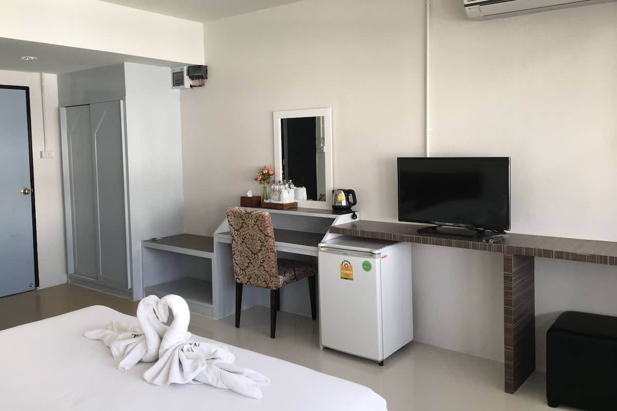 Habitación de hotel con cama, escritorio con computadora, televisor, minibar y aire acondicionado.