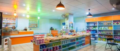 Una tienda luminosa con estantes llenos de diversos productos, un mostrador y una zona de estar.