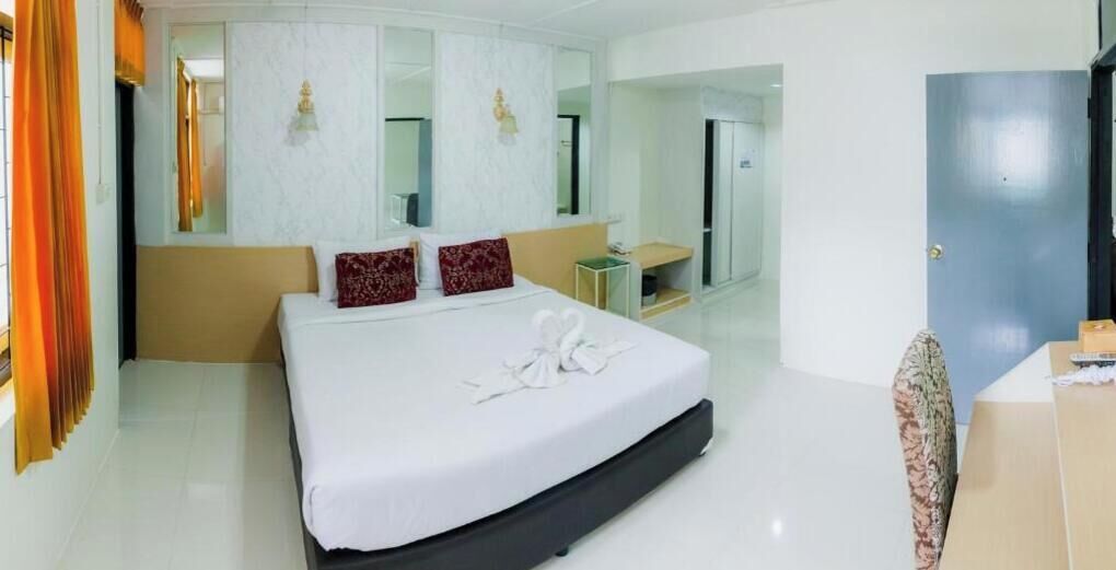 A hotel room with a large bed, a bedside table, a mirror, and a wardrobe.