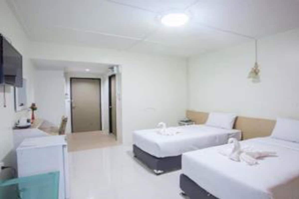 Habitación de hotel con dos camas, un escritorio, una silla y una mesita.