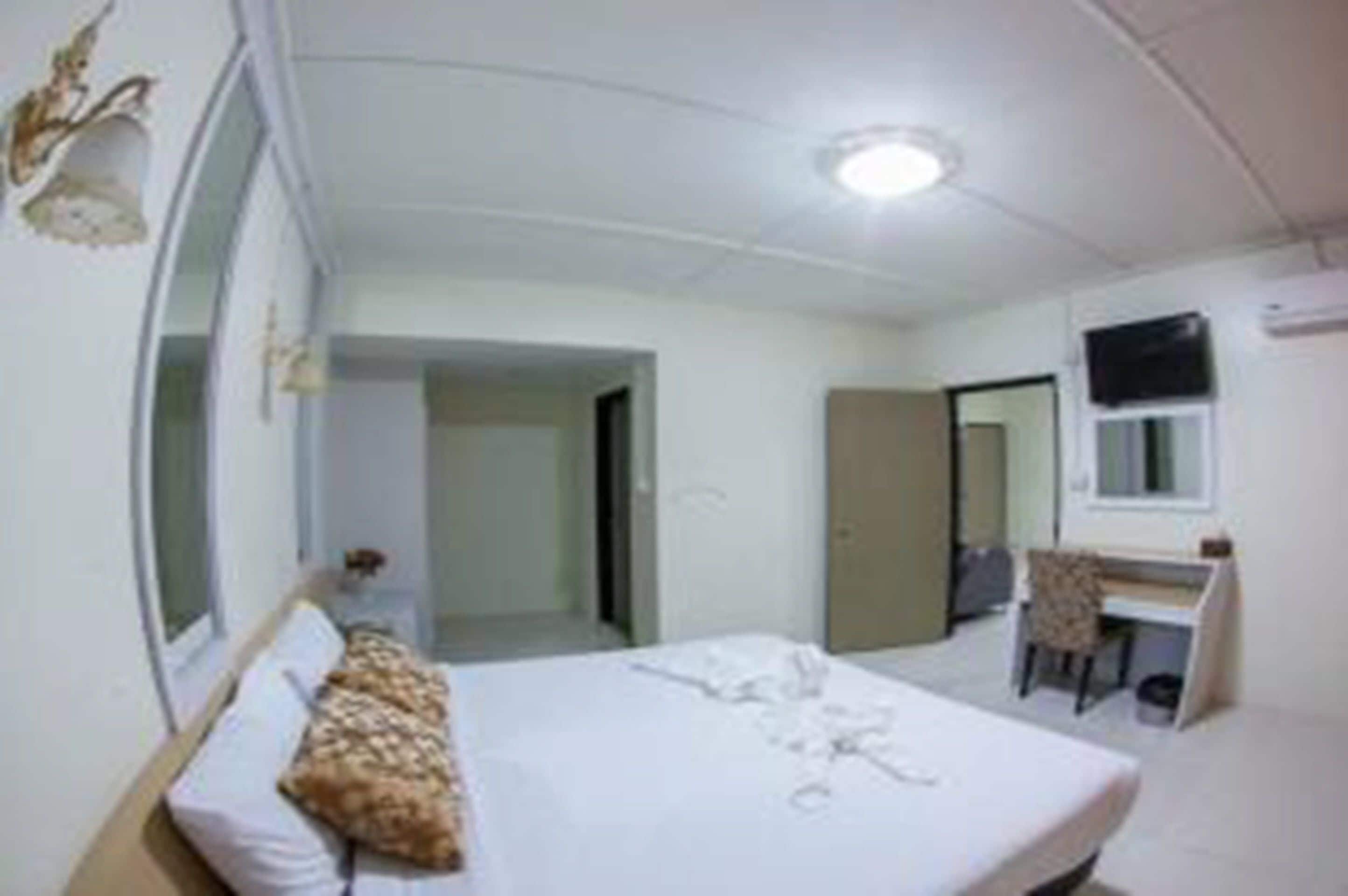 A bedroom with a bed, a desk, and a mirror.