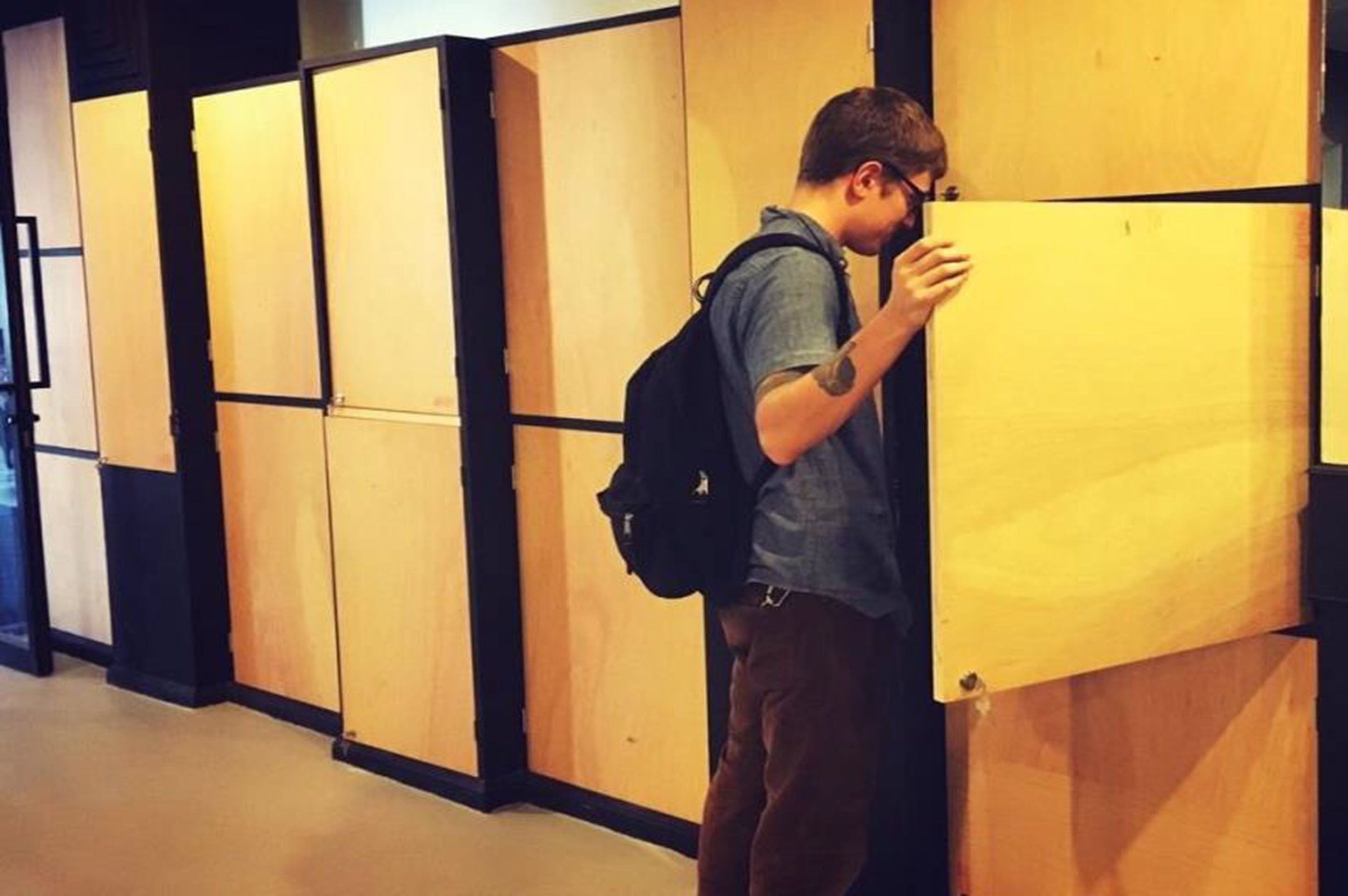 A person standing in front of a wooden panel wall with a large panel partially open.