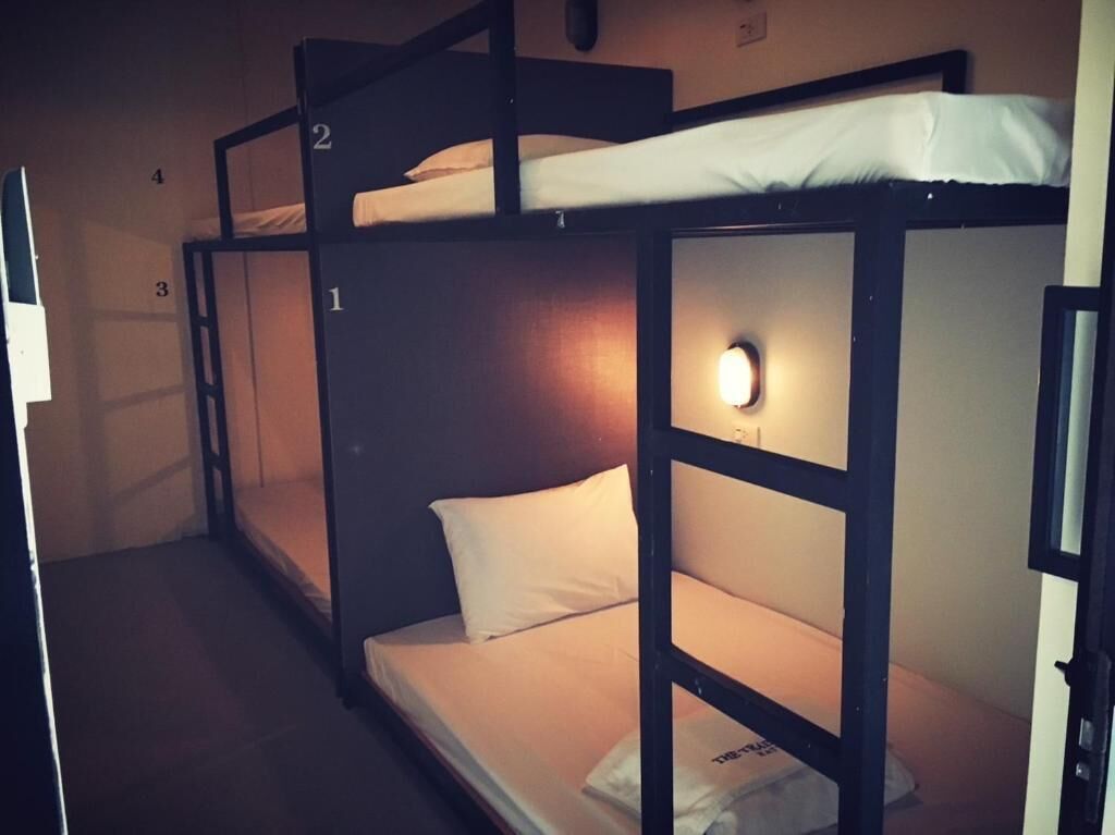Een slaapkamer met een stapelbed van drie niveaus, elk voorzien van een nummer.