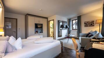 A hotel room with a large bed, a desk with a chair, a television, and a small table.
