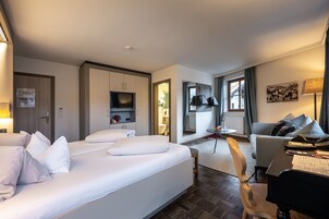 Habitación de hotel con una cama grande, un escritorio con silla, un televisor y una mesita.