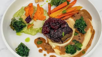 Ein Teller mit verschiedenen Gemüsesorten, einem Stück Fleisch und einer Soße.