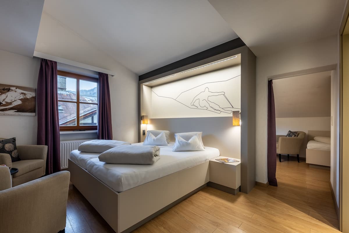 A modern hotel room with a large bed, a desk, and a chair.
