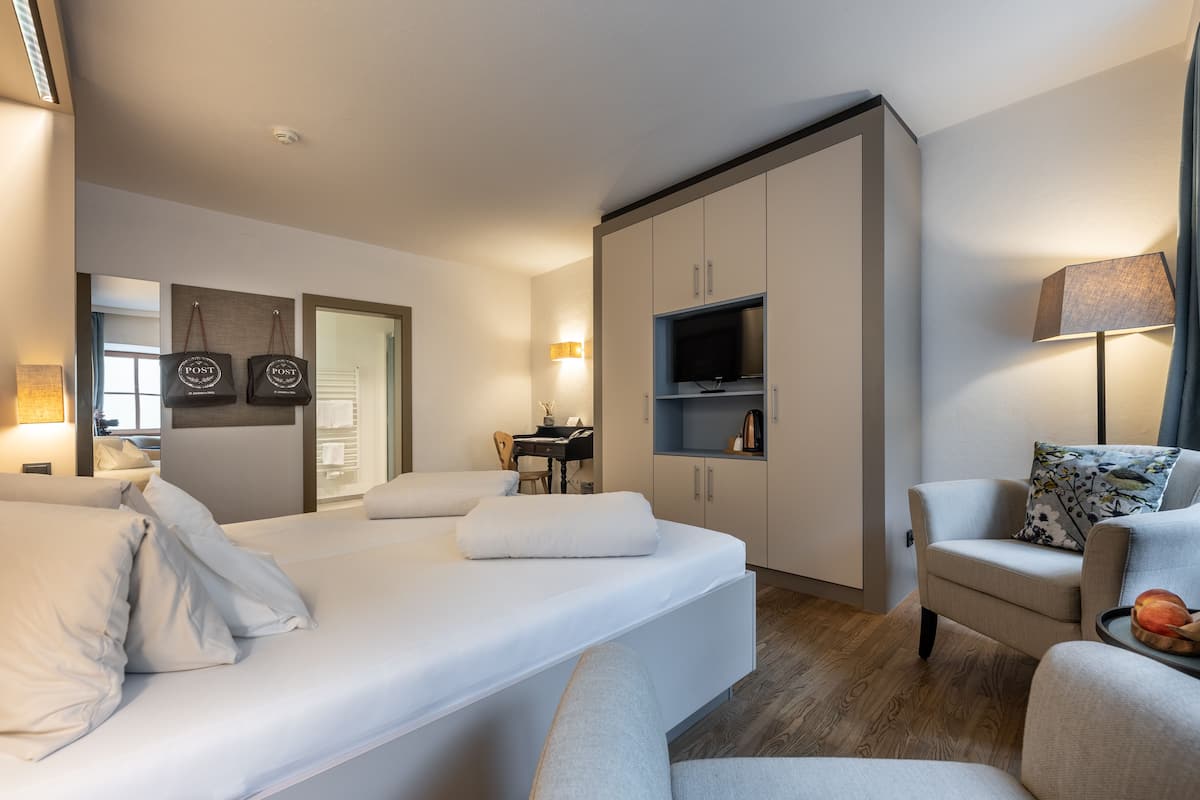 A modern hotel room with a bed, a desk, a chair, a TV, and a wardrobe.