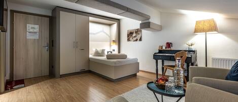Una sala moderna con un sofá, una mesita de centro y una lámpara. Hay una cama con cabecera y un escritorio con una silla.
