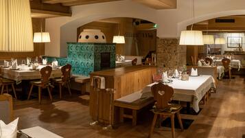 A restaurant with wooden tables and chairs, a central bar area, and pendant lighting.